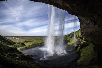 Una vista desde detrás de las aguas de la cascada de Seljalandsfoss en la costa sur de Islandia.