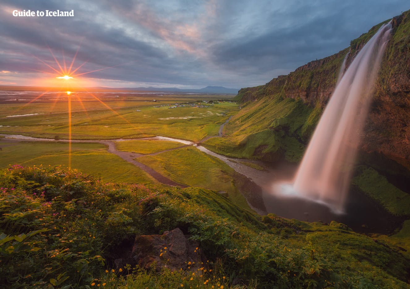 La cascada mágica de la cascada Seljalandsfoss bañada por la luz del sol en una puesta de verano.