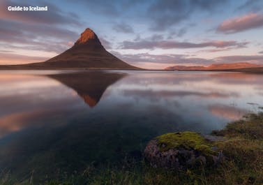Berget Kirkjufell avspeglat i en sjö under en midsommarkväll på Island.