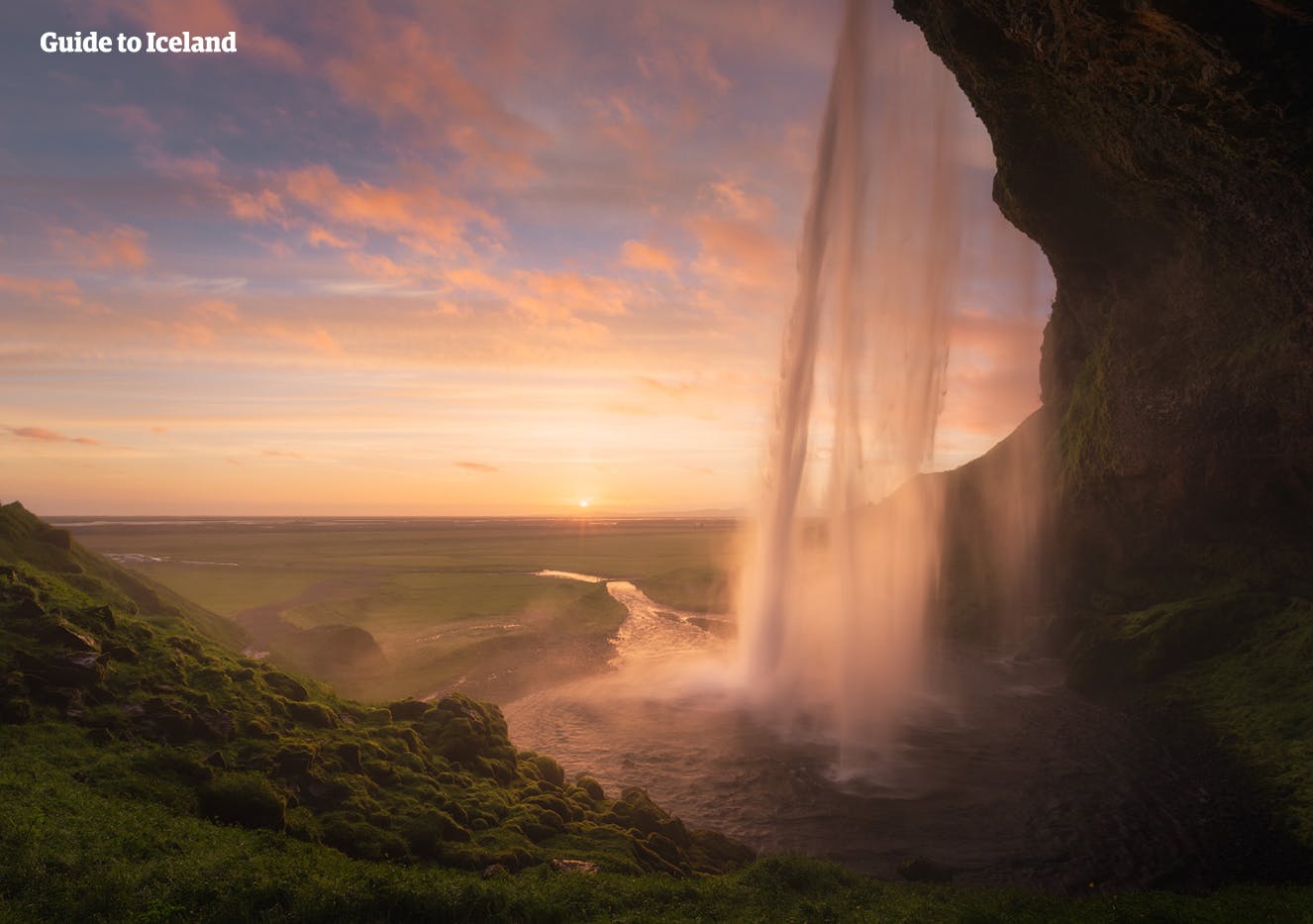 Rund um die Sommersonnenwende im Juni können Besucher hinter dem Wasserfall Seljalandsfoss stehen und um Mitternacht beobachten, wie die Sonne auf dem südlichen Horizont balanciert, aber nie dahinter versinkt.