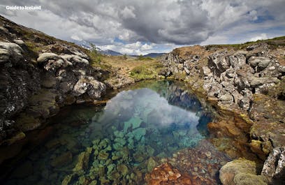 De l'eau de fonte provenant du glacier Langjökull plonge dans un champ de lave et voyage sous terre jusqu'aux ravins du Parc National de Thingvellir ; ce long processus de filtration donne l'eau la plus pure au monde, toute l'année en Islande.