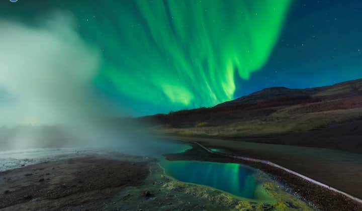A column of steam rises before Iceland's aurora borealis.