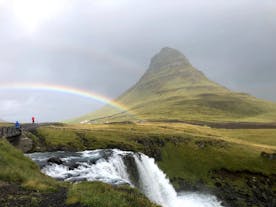 A rainbow forms in front of the Kirkjufell mountain.
