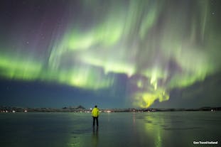 A man stands under the northern lights during a private tour in Iceland.