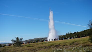 Strokkur geyser in Iceland erupts as tourists watch in amazement.