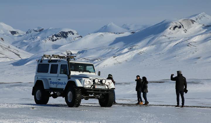 A super jeep parking in the snow with mountains in the background during winter in Iceland.