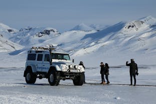A super jeep parking in the snow with mountains in the background during winter in Iceland.