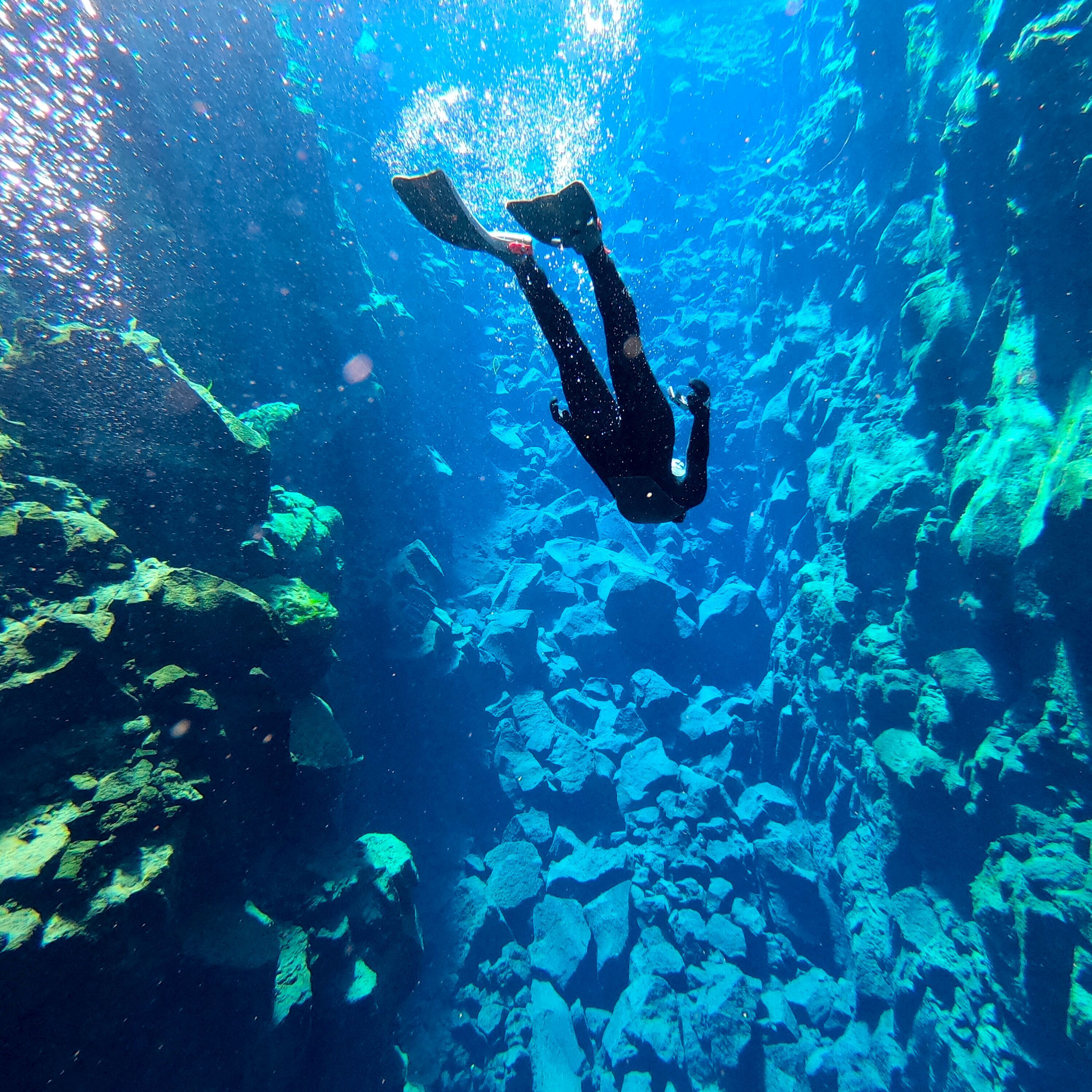 A tour participant uses flippers to dive down further into Silfra