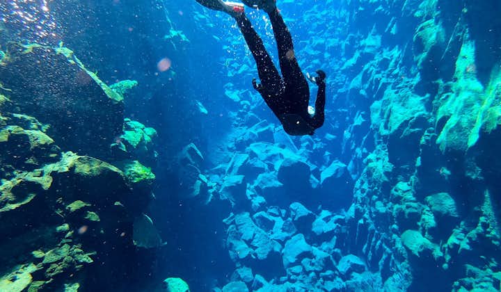 A tour participant uses flippers to dive down further into Silfra