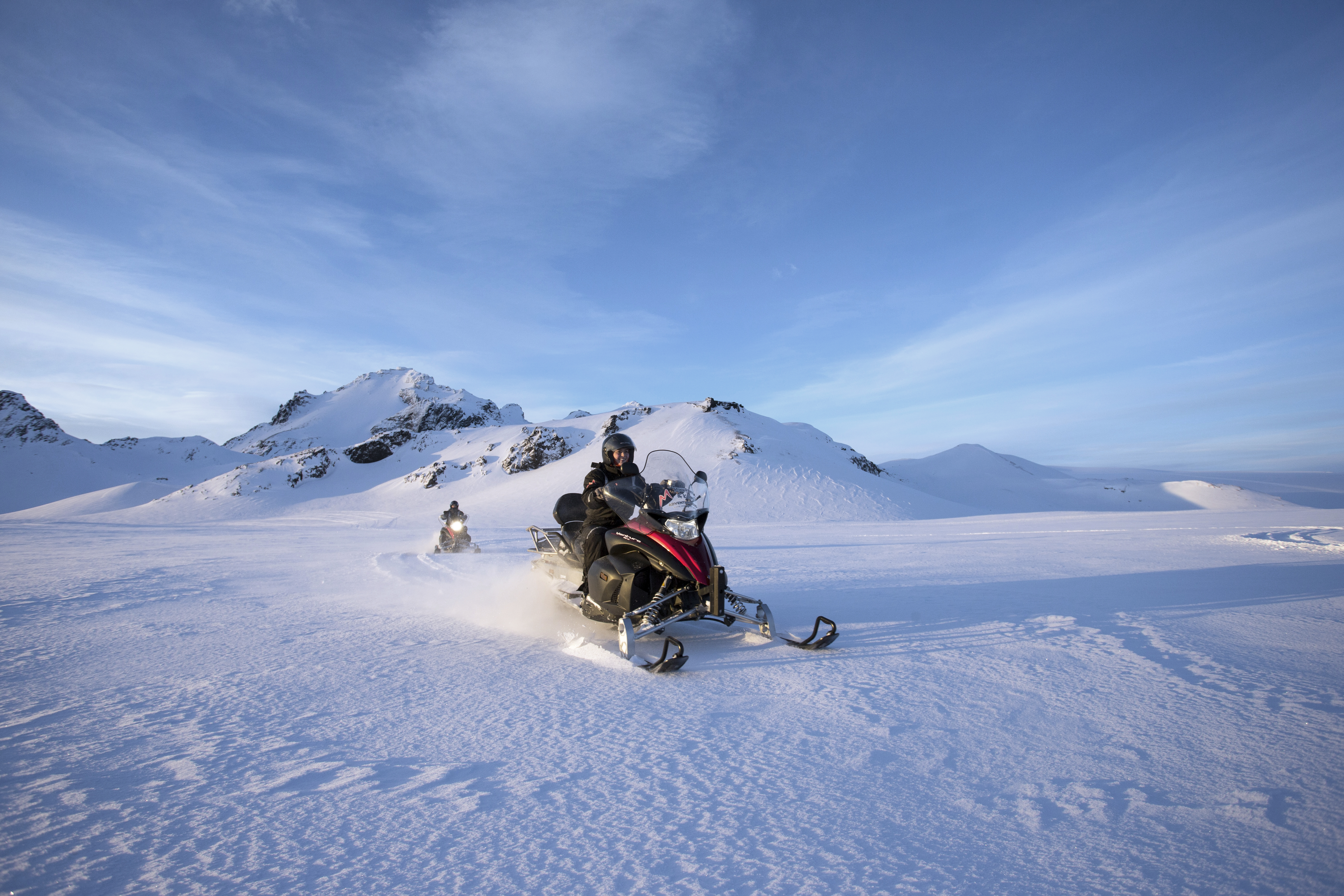 Snowmobiling Tour on Langjokull Glacier on a blue-sky day.