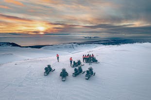 A group of people are seen from above on their snowmobiles on top of a glacier in Iceland.