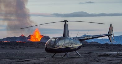 Et helikopter lander foran et aktivt vulkanutbrudd på Island.