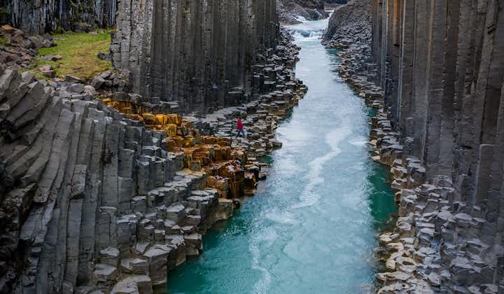 Hexagonal basalt rock column walls lining a river canyon in east Iceland.