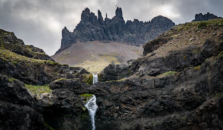 Dark volcanic rock formations standing over a waterfall.