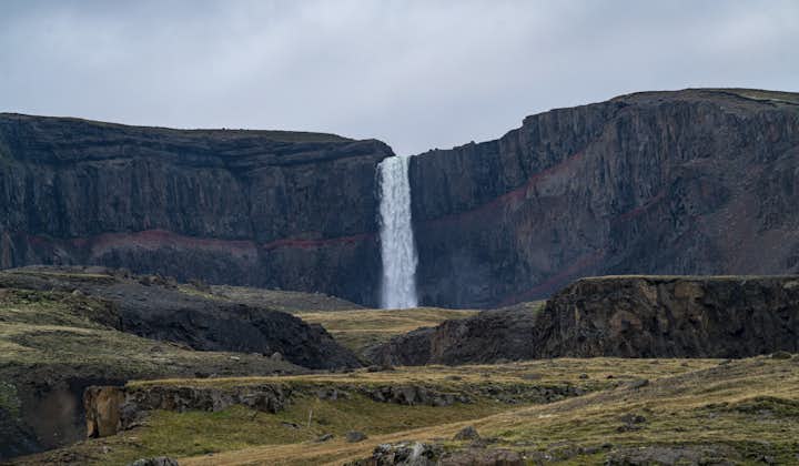 A waterfall cascading town multi-layered rock in east Iceland.