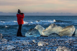 A traveller taking pictures of ice that has washed onto the shores of the diamond beach.