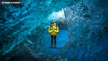 Kobieta w żółtym płaszczu w lodowcowej jaskini Vatnajokull.