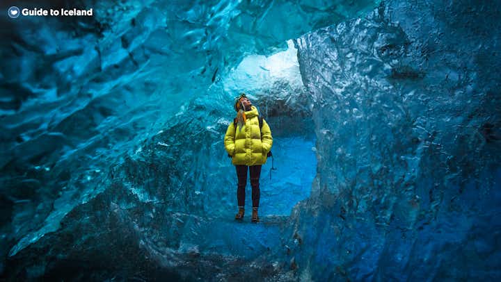 Una donna con una giacca gialla nella grotta di ghiaccio di Vatnajokull