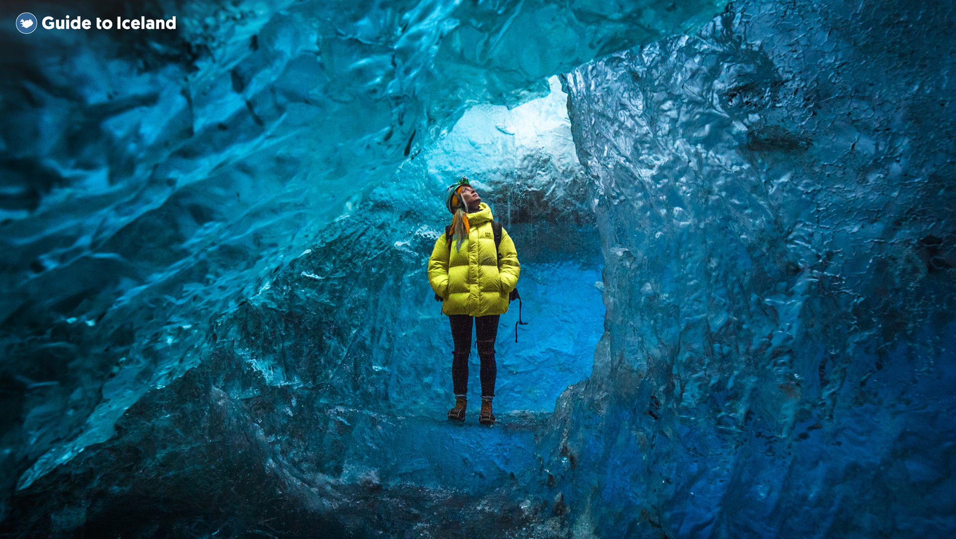 Женщина в желтой куртке на фоне ледниковой пещеры