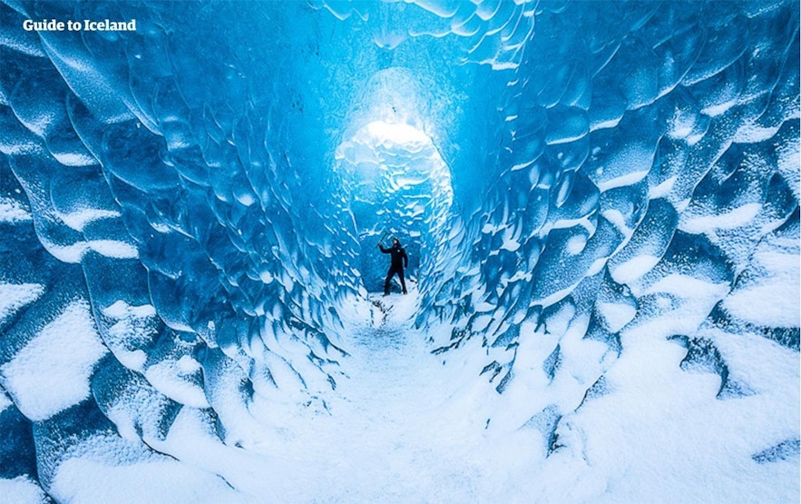 A man wields an ice axe in a blue ice cave