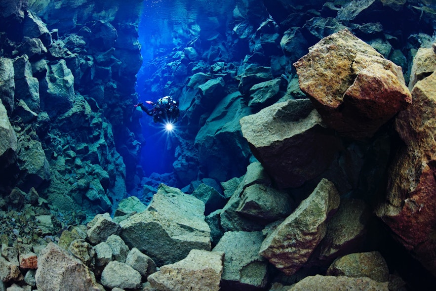 Man diving in Silfra fissure with a light in his hand