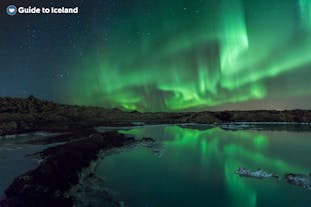 Die Nordlichter leuchten am Himmel über einem Gewässer auf der Halbinsel Reykjanes in Island.