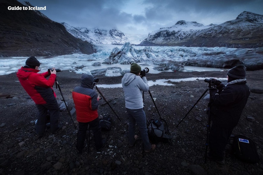 Eine Reisegruppe stellt Stative auf, um einen Gletscher zu fotografieren.