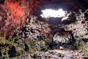 Inside Raufarholshellir Lava Tunnel which has a red glow on the walls.