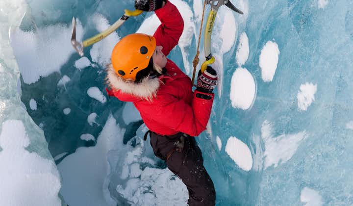 Person climbing Solheimajokull glacier using axes and crampons.