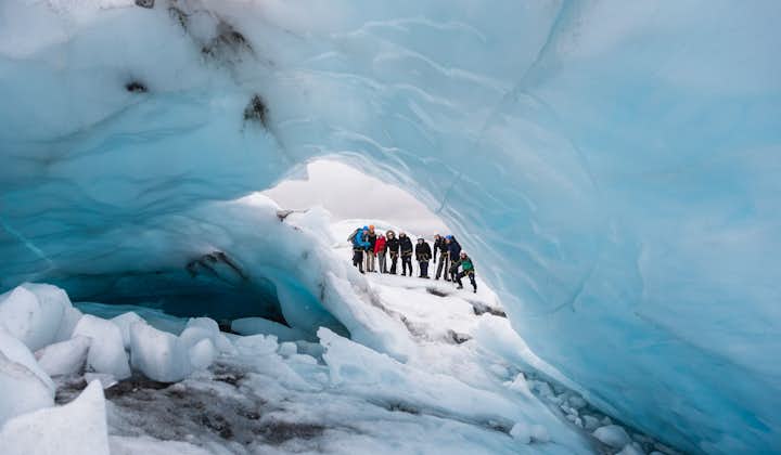 The group of glacier hikers peeking out of an ice tunnel