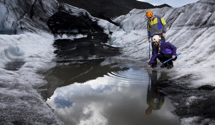 Two people in safety gear exploring a small glacier lagoon in Iceland.
