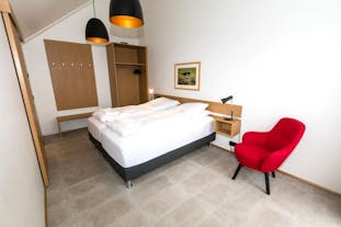 Et rom med dobbeltseng, stol, lamper og skap i Hrimland Top Floor Luxury Apartment #2.