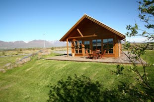 The exterior view of the wooden Family cottage in North Iceland with a table and chairs on the patio, countryside surroundings, 