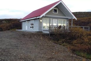 The exterior view of the Stundarfridur 4 in West Iceland, a three-bedroom house with a front patio and countryside surroundings.