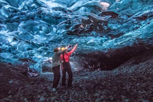 Two people in an ice cave in Iceland, pointing out some of the unique features of the ice.