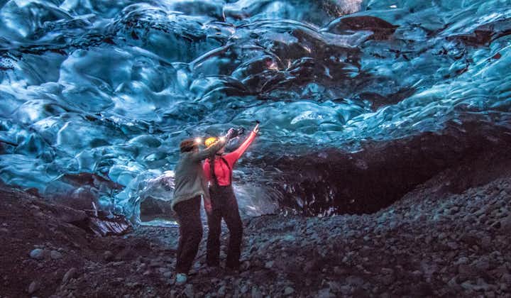 Two people in an ice cave in Iceland, pointing out some of the unique features of the ice.
