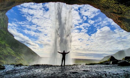 A man silhouetted against the stunning Seljalandsfoss waterfall in South Iceland