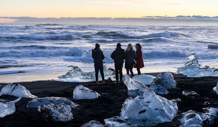A group of people standing at the Diamond Beach in Iceland at Golden Hour