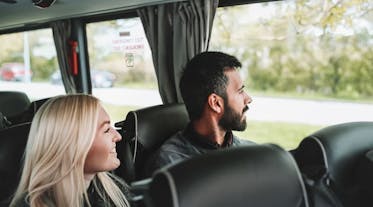 Two people look out the window while sitting on a bus.