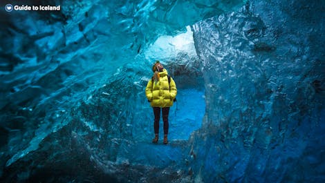 A woman stands inside a blue ice cave in Vatnajokull National Park.