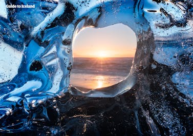 The ocean photographed through a piece of clear ice, sitting on the shore of the Diamond Beach in Southeast Iceland.
