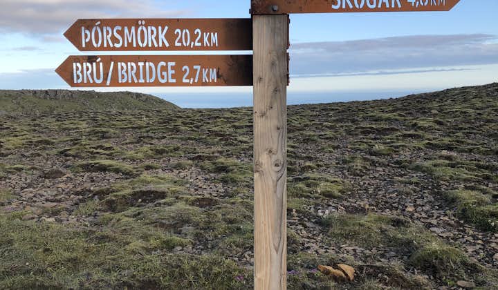 A sign on the Fimmvorduhals hiking trail shows the distances to Thorsmork nature reserve and a bridge in one direction and Skogar in the other.