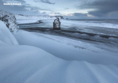 Den svarte sandstranden Reynifjara i  Sør på Island, dekket av et tynt teppe av snø.