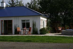 Farma Jadar: parterowy domek w kolorze białym, przed którym stoi drewniany stół i krzesła.