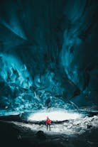 A person is dwarfed by the incredible scale of an ice cave near Jokulsarlon in Southeast Iceland.