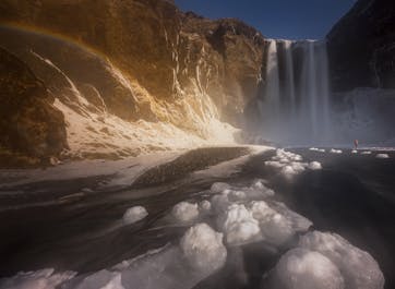 La cascade de Skogafoss sur la côte sud de l'Islande, photographiée en hiver avec de la glace et de la neige au sol.