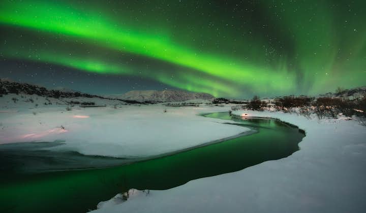 A magical dance of the aurora borealis occurs over a snowy landscape in Iceland.