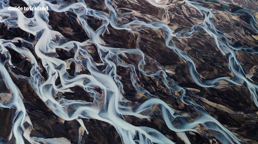 A river network slices up a plain of black sands in Iceland.