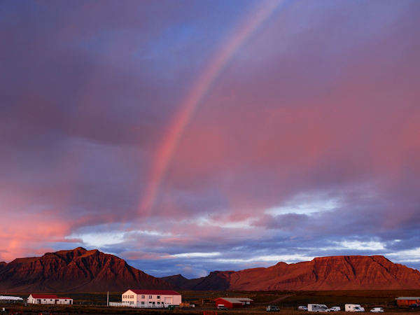 A rainbow arches over Snorrastaðir.