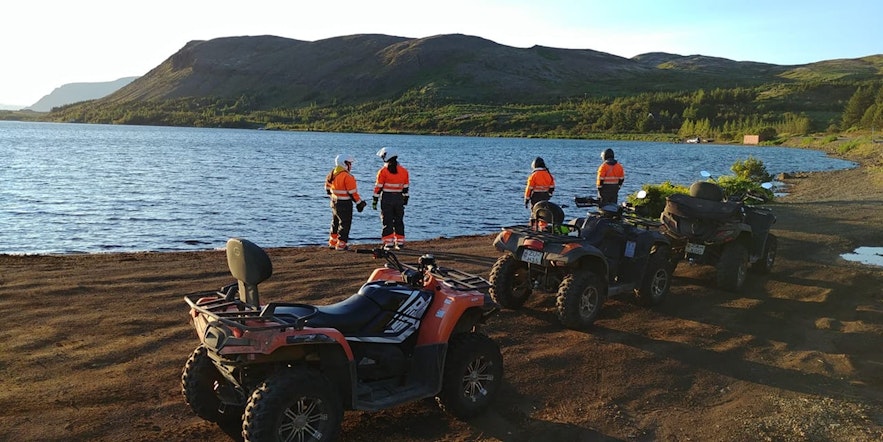 Quadbikers break for photos by a lake in Iceland.